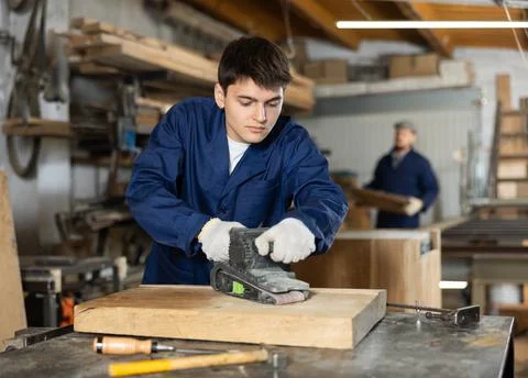 Portrait of young man carpenter using electric sanding machine to polish wood Foto stock