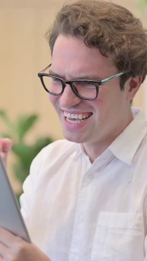 Portrait of Young Man Celebrating on Tablet in Modern Office, Vertical Video Vídeos de archivo 340034066