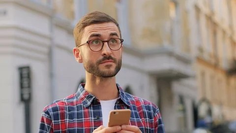A portrait of a young man in the city looking up and then into his phone Stock Footage 81049902