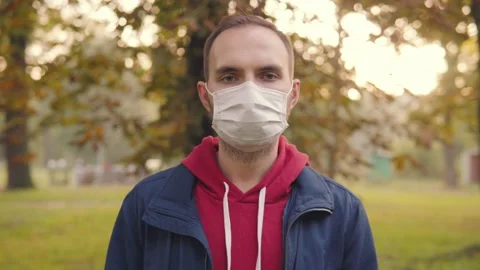 Portrait of a young man in a disposable protective medical mask who stands in a Stock Footage 161931033