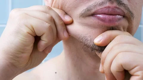 Portrait of young man doing chin massage against background of blue tiles. Stock Footage 329726878