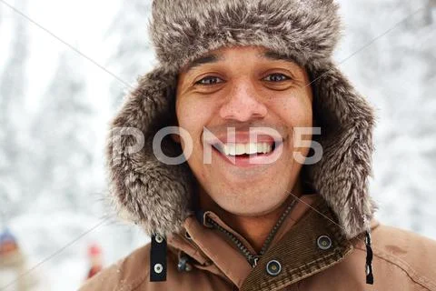 Portrait of young man in fur hat smiling at camera Stock Photos