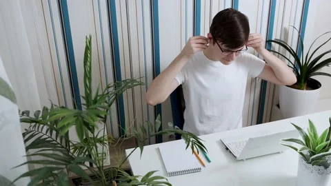 Portrait of a young man with glasses during online training, puts on headphones Stock Footage 169862433