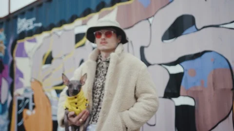 Portrait young man with hat in red sunglasses holding dog wear yellow clother in Stock Footage 106557353