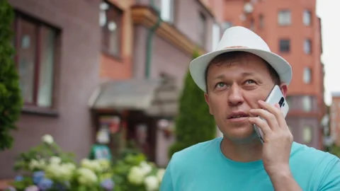 Portrait of a young man in a hat talking on a mobile phone in the street Stock Footage 139886546