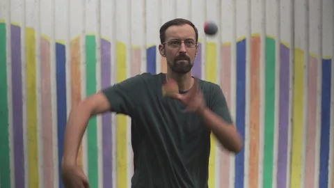 Portrait of young man juggler while quickly juggling balls with hands, close up. Stock Footage 94929930
