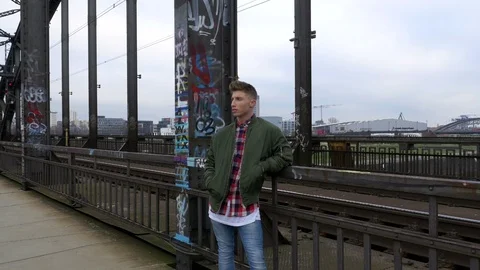 Portrait of young man leaning arm on bridge rail and looking away Stock Footage 86813239