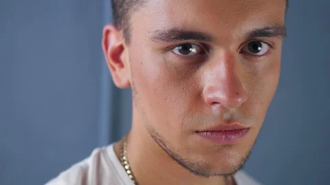 Portrait of a young man looking into the camera and putting on a military fabric Stock Footage 118894675