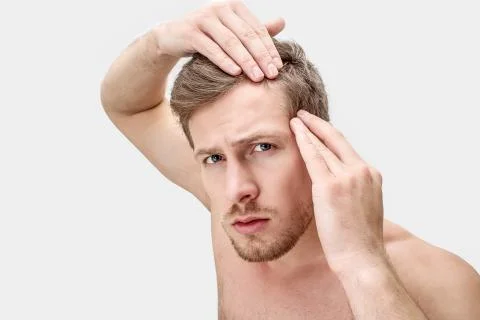 Portrait of young man looking on camera. He hold hands on hair. He is worried Stock Photos