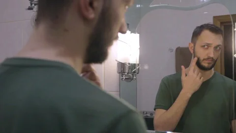 Portrait of young man looking at his reflection in a bathroom mirror  Video stock 104021762