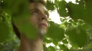 Portrait Of Young Man Looking Through Tree Branches In Forest. Stock Footage
