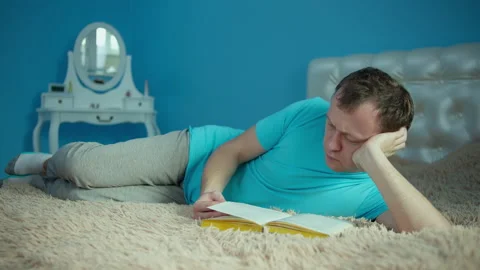 Portrait of a young man lying with a book in his hands Stock Footage 145694635