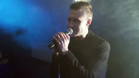 Portrait of a young man with a microphone on a background of smoke Stock Footage 105812481
