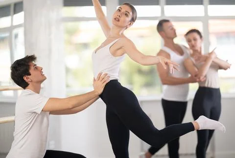 Portrait of young man practicing in classical ballet pose with support with Stock Photos