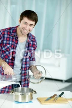 Portrait of young man preparing food, looking at camera and smiling Stock Photos