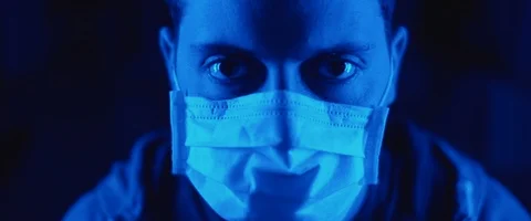 Portrait of a young man putting on a protective mask, blue lighting. Stock Footage 126357920