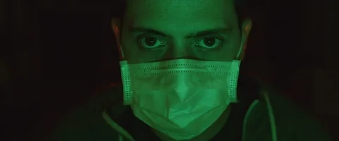 Portrait of a young man putting on a protective mask, green lighting. Stock Footage 126357940