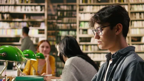 Portrait of young man reading open book at library study table Stock Footage 336359062