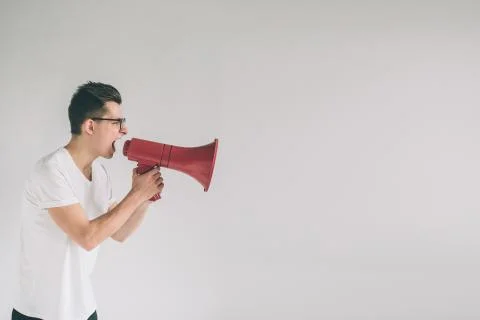 Portrait of young man shouting using megaphone over background Nerd is wearing Foto stock