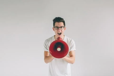 Portrait of young man shouting using megaphone over background Nerd is wearing Foto stock