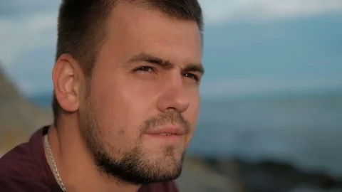Portrait Young man sits on beach in summer evening outdoors. Stock-Footage 80164855
