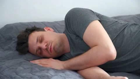 Portrait of young man sleeping in bed wearing in jeans and t-shirt after party. Stock Footage 153366632