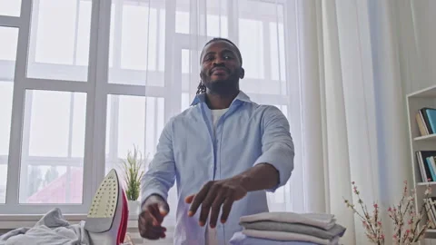 Portrait of young man with a stack of freshly ironed clothes, household chores Stock Footage 188229984