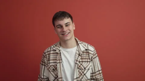 Portrait of young man stand in front red background studio shot Stock Footage 300789641