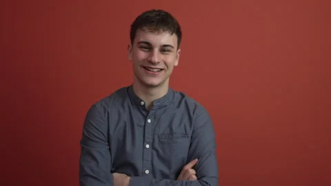 Portrait of young man stand in front red background studio shot Stock Footage 300789646