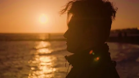 Portrait of young man standing on the beach, watching beautiful sunset. Sand sea Stock Footage 80438941