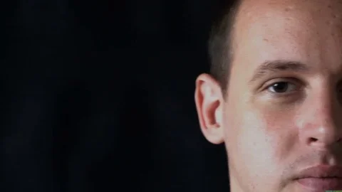 Portrait of a young man staring at camera,black background Stock Footage 76525442