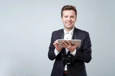 Portrait of a young man in suit using tablet computer over gray background an Foto stock