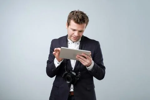 Portrait of a young man in suit using tablet computer over gray background an Stock Photos