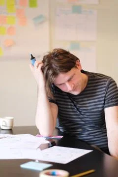 Portrait of a young man at a table at work. Stock Photos
