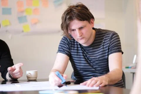 Portrait of a young man at a table at work. Stock Photos