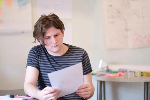 Portrait of a young man at a table at work. Stock Photos