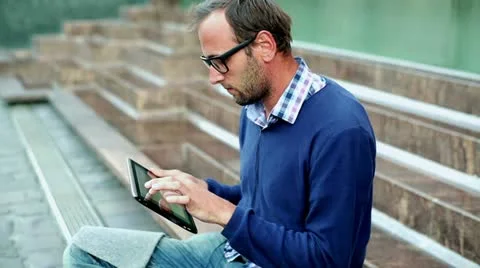 Portrait of young man with tablet computer sitting on the stairs, outdoors Stock-Footage 12389663