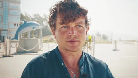 Portrait of the young man talking during an interview in the coastal town during Stock Footage 337287593