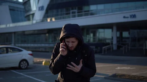 Portrait of a young man talking on a mobile phone in the street on a background Stock Footage 93334581