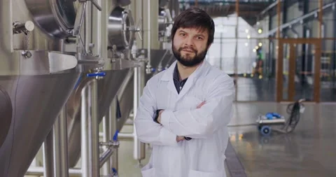 Portrait of young man technologist in lab coat with arms crossed posing at 스톡 동영상 148230274