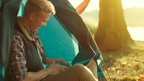 Portrait of young man using laptop on hiking at sunset Stock Footage 98672220