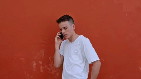 Portrait of a young man using the phone and looking to the camera with a orange Vidéo 120515266