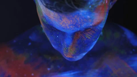 Portrait of young man in UV paint. Bright fluorescent body art glows in darkness Stock Footage 132273297