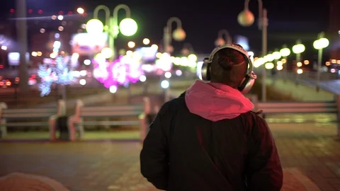 Portrait of young man wearing head phones while walking on the street in the Stock Footage 89347553