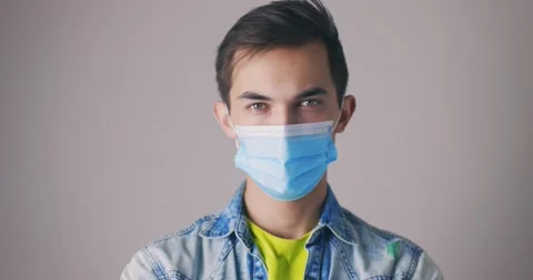 Portrait of a young man wearing protective face mask at grey background. Studio Stock Footage 147998418