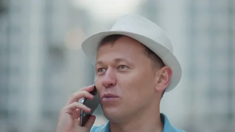 Portrait of a young man in a white hat talking on a mobile phone, close up Stock Footage 142958768
