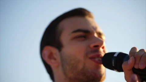 Portrait of a young man who sings a song on the street in the daytime Stock Footage