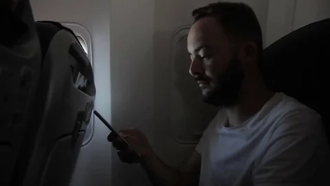 Portrait of young man, who is using his smartphone in the aircraft. Video stock 85275538