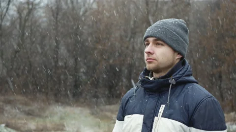 Portrait of a young man in winter clothes enjoys snow in the face Stock Footage 124467100