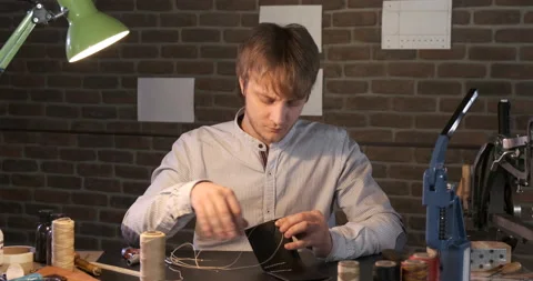 Portrait Of Young Man at Work, Man Sews Wallet Using Needle and Thread Stock Footage 133009629